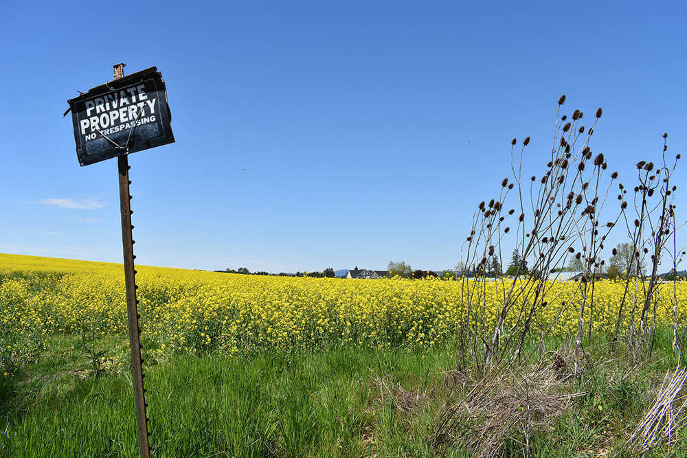 Private property sign in front of field with houses in the background