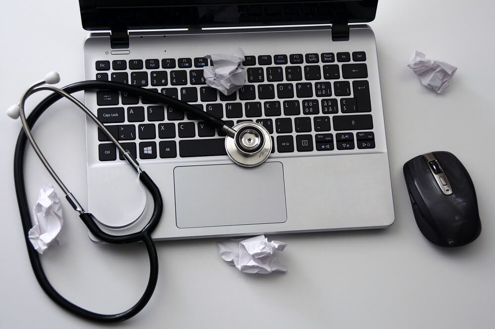 Stethoscope and crumbled paper sitting on laptop