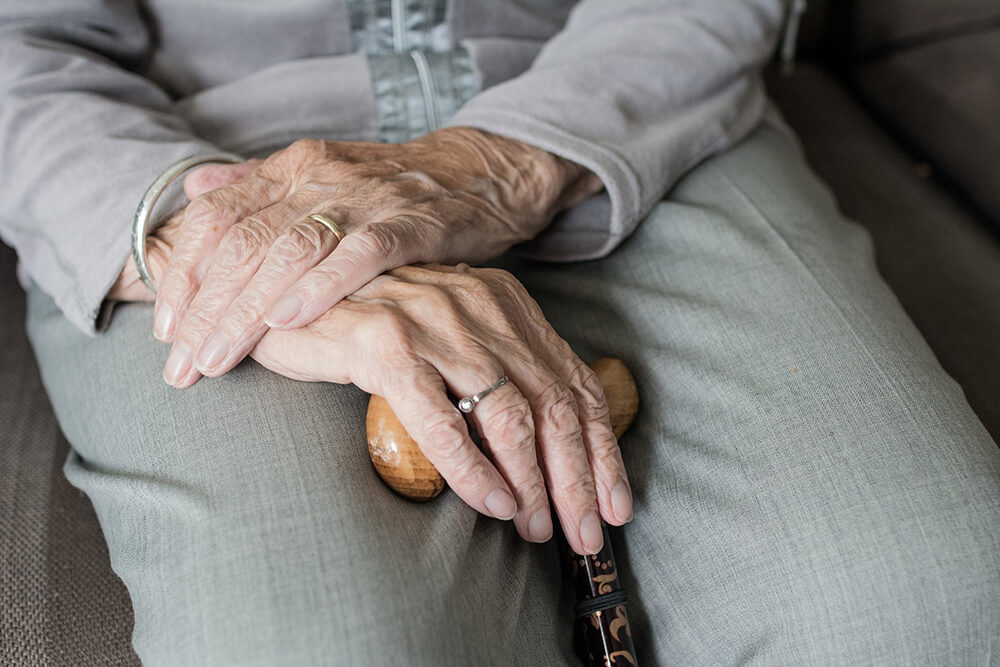 Elderly person sitting with hands in lap